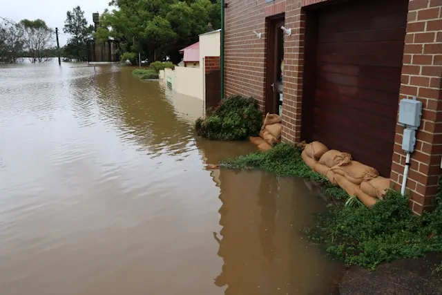 Sacos de arena colocados en la puerta de un garaje para frenar el agua de una calle inundada, la medida de emergencia que no sustituye a una buena cobertura de daños por agua en el seguro de hogar