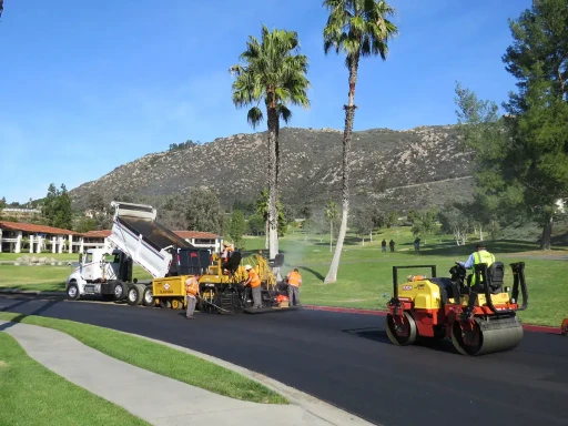 Rolling compactor following right behind asphalt paving machine