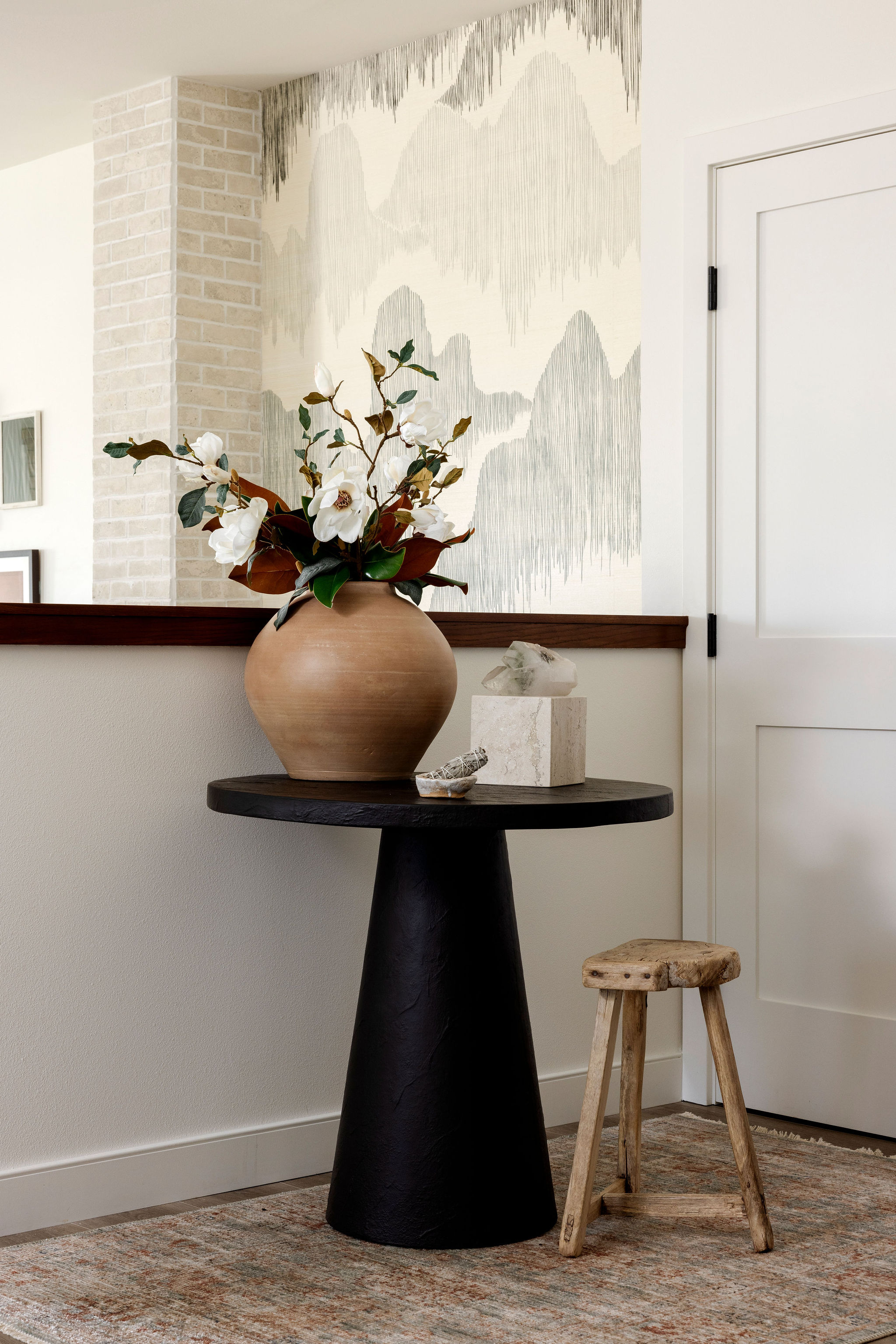 Welcoming entryway featuring a sleek round table, a statement stool, and natural textures that set the tone for the home's serene aesthetic