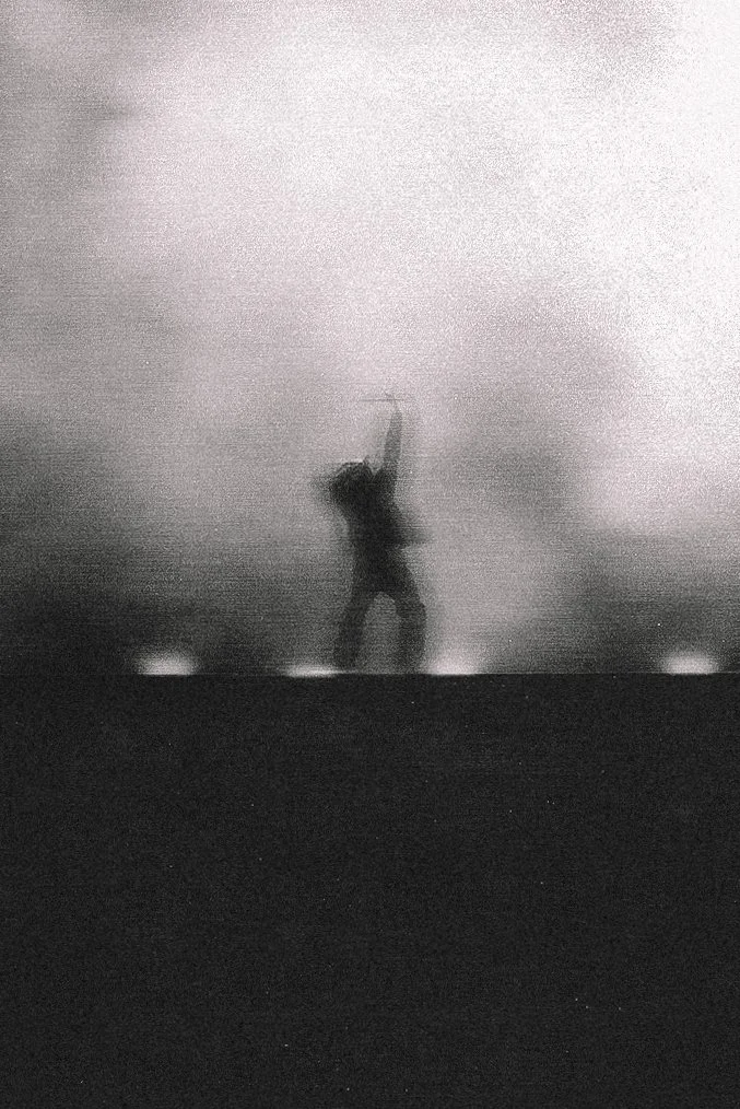 Distant performer surrounded by smoke in black and white