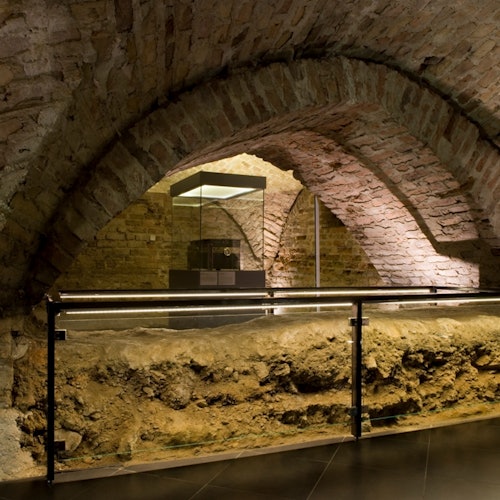 Underground space with brick archways, a glass display case, and a metal railing.