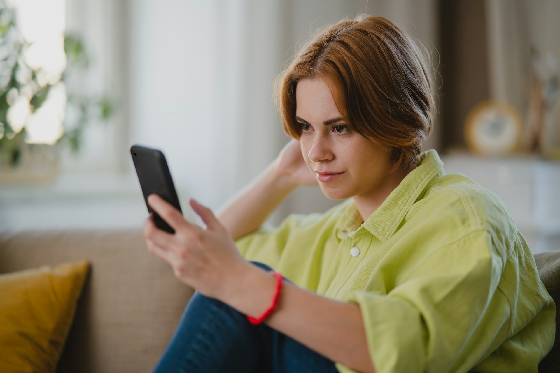 girl looking at phone sitting on the sofa