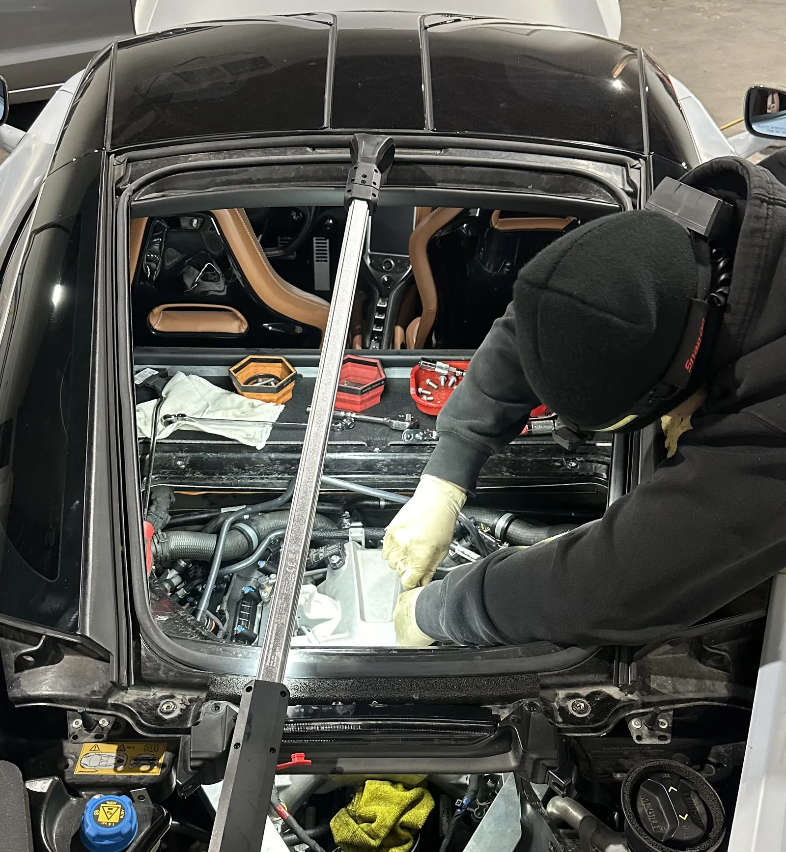 Technician leaning into the engine bay of a mid-engine car at 714 Technik