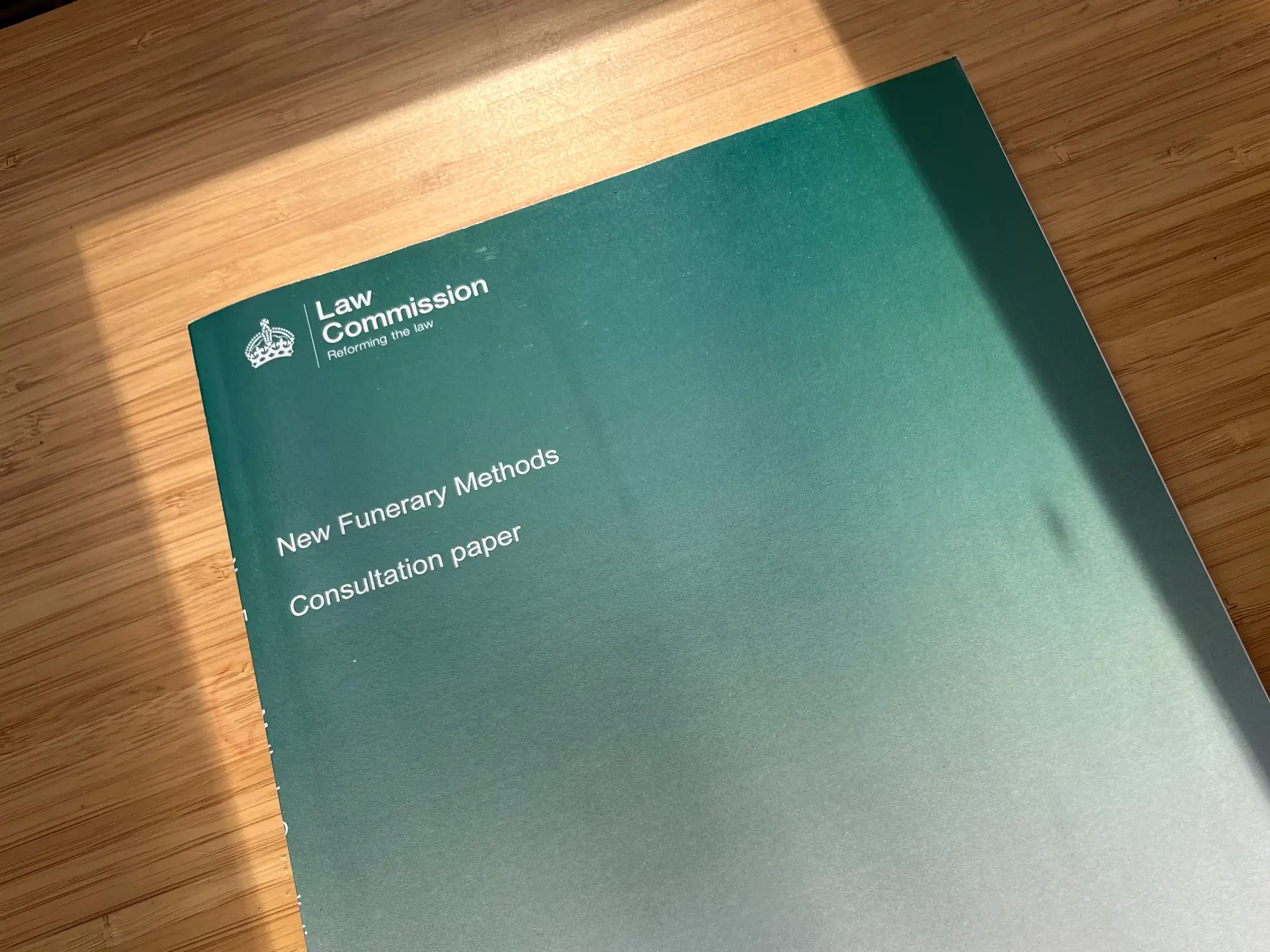 A green portfolio or folder resting on a wooden surface, partially open with text visible on the cover.