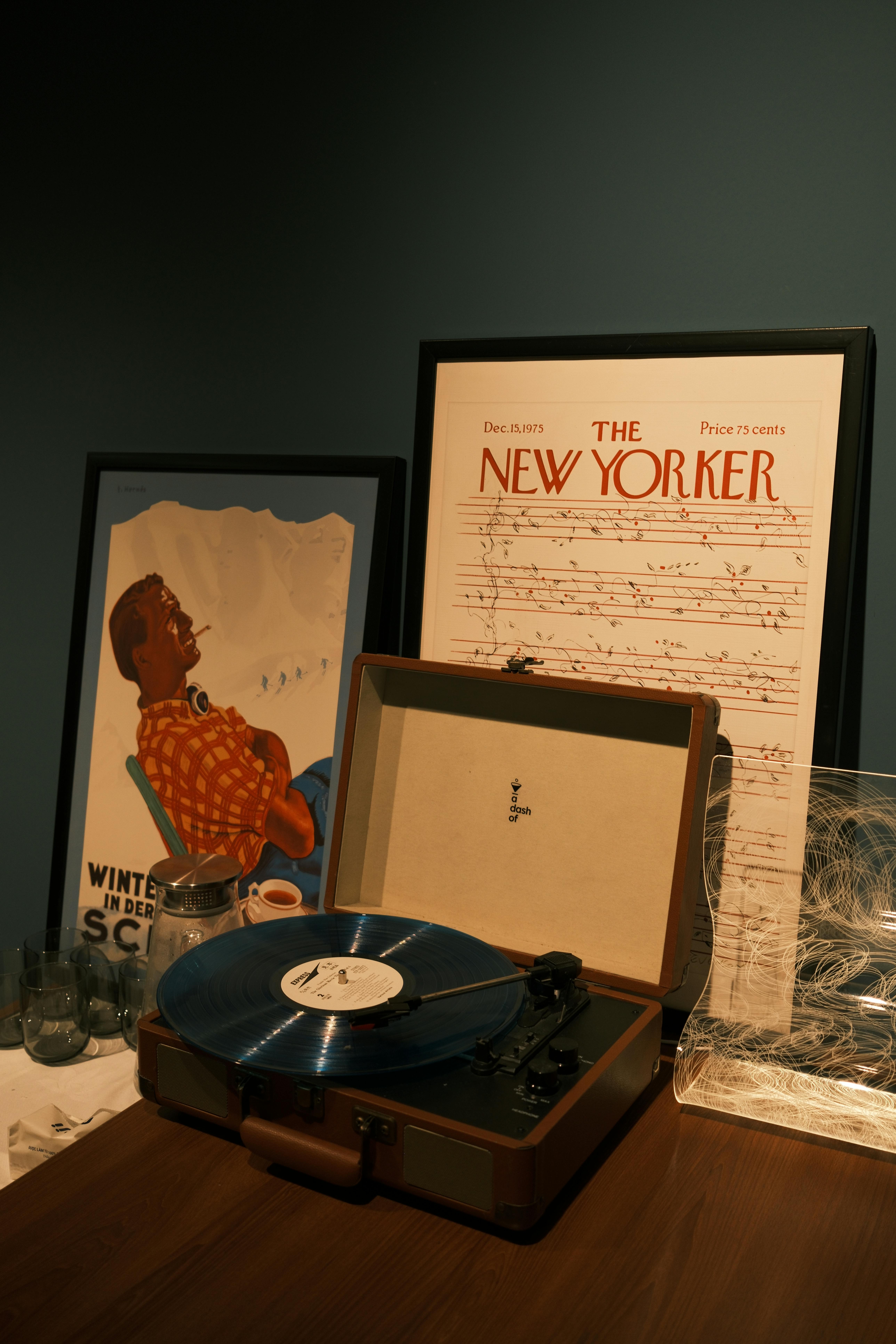 Vintage record player with blue vinyl, New Yorker poster, and ski poster.
