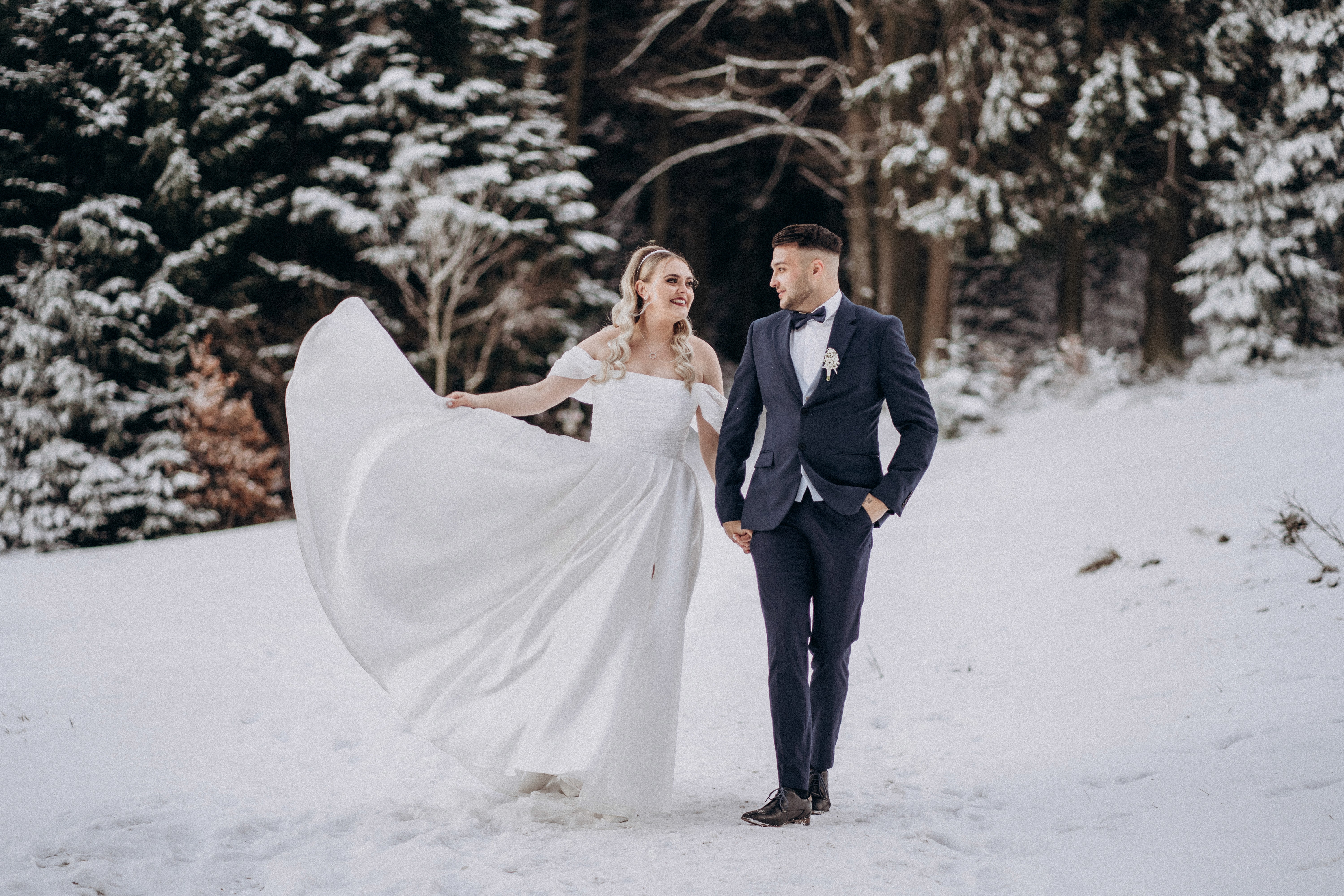 Winterliche Hochzeitsfotografie in Bogen, Niederbayern – Brautpaar spaziert im Schnee.