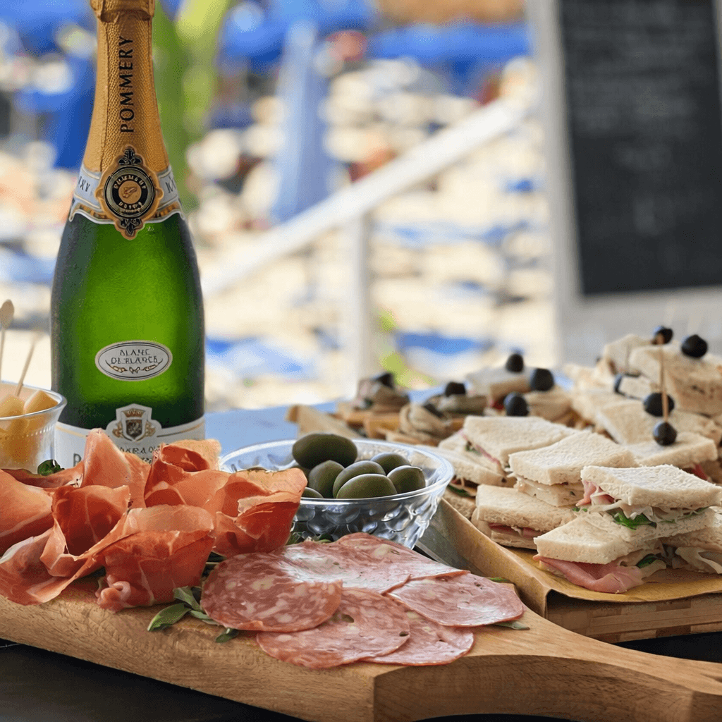 Tagliere di salumi e formaggi con champagne sulla spiaggia di Urlamare