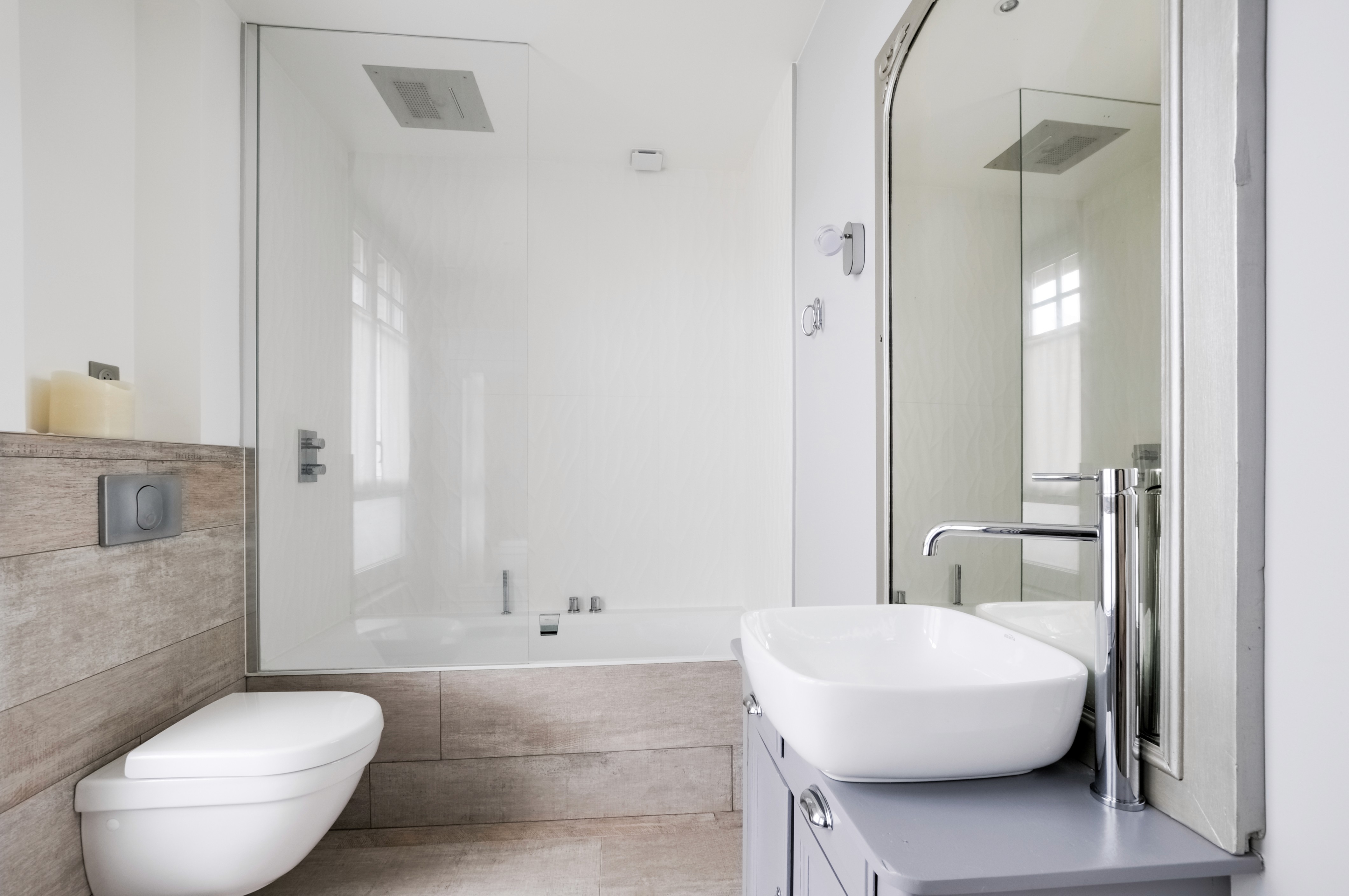 Rénovation salle de bains Seine-et-Marne avec toilettes murales, baignoire rectangulaire, pare-douche verre et accents bois, architecte d'intérieur.
