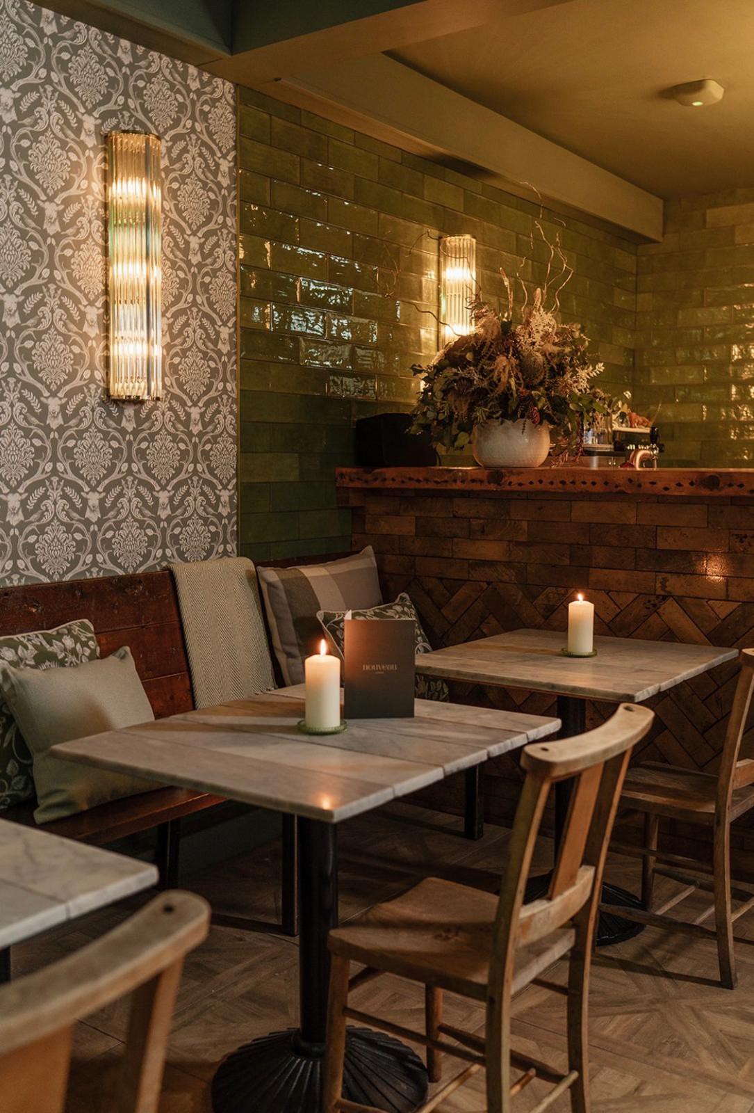 Person wearing a beige apron whisking green matcha tea in a ceramic bowl on a kitchen counter.