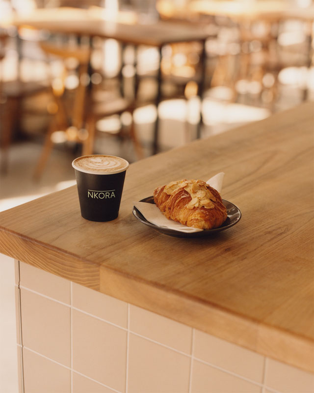 A coffee cup and a croissant inside NKORA Coffee Shop