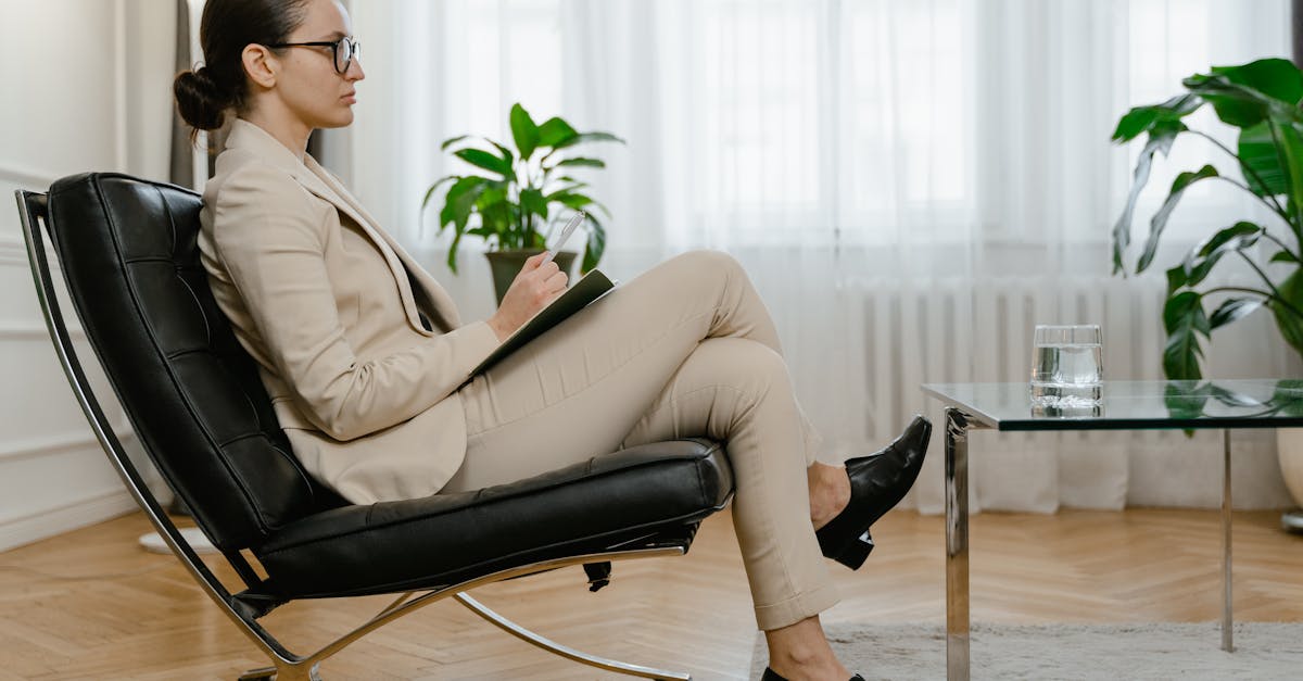 Professional woman in corporate attire holding a clipboard, seated in a modern workspace.
