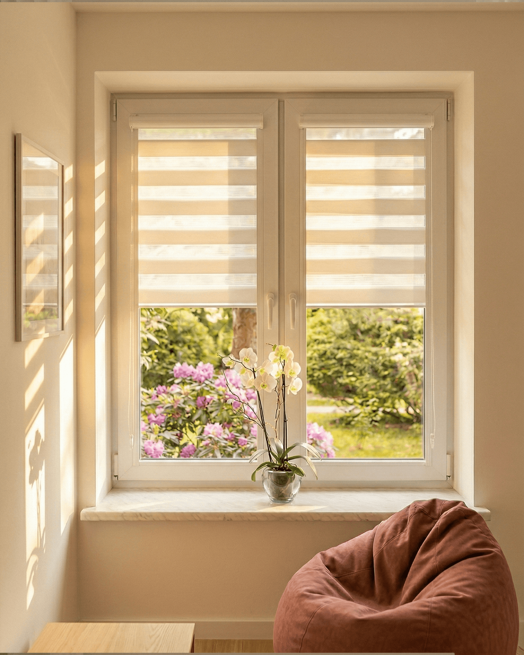 Biała roleta Dzień i Noc zamontowana na białym oknie PCV w przytulnym kąciku do czytania z pufą. HeyShade Pruszków – nowoczesne rolety materiałowe zapewniające prywatność i kontrolę światła.