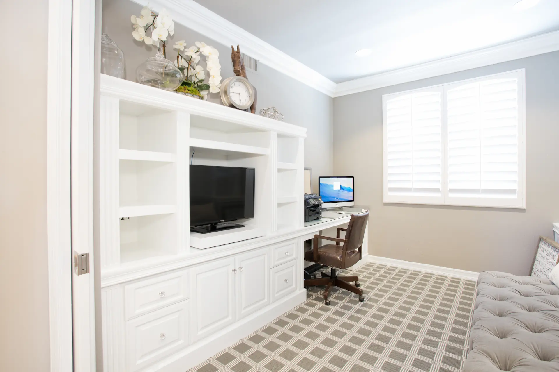 Home office with built-in shelves, TV, and tufted bench in Newport Beach Remodel.