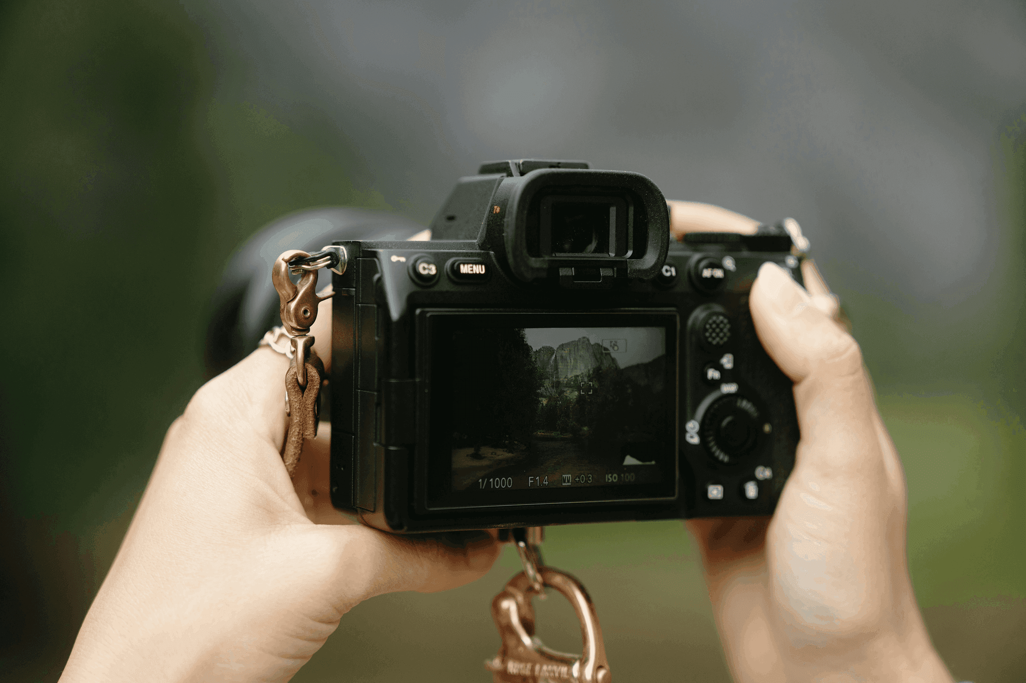 Hands holding camera, capturing a landscape scene.