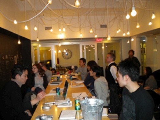 A group of people sitting at a conference table, facing each other inside a room.