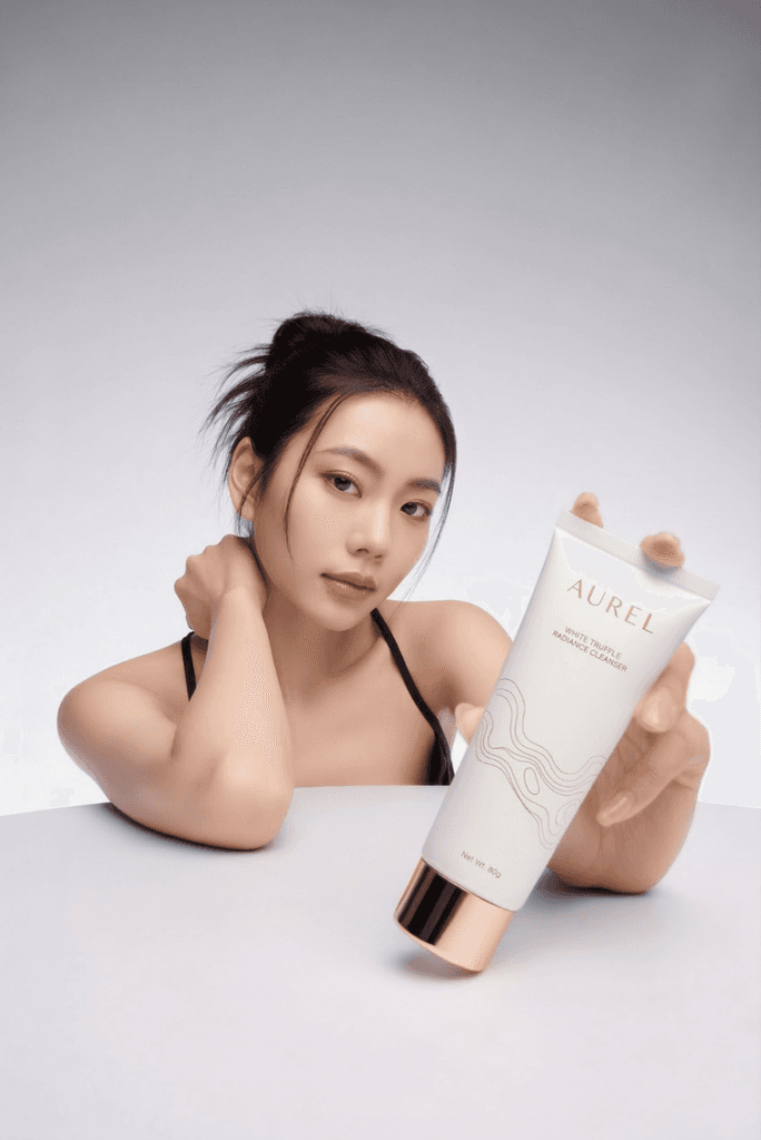 Woman holding a skincare product tube in a clean studio setting