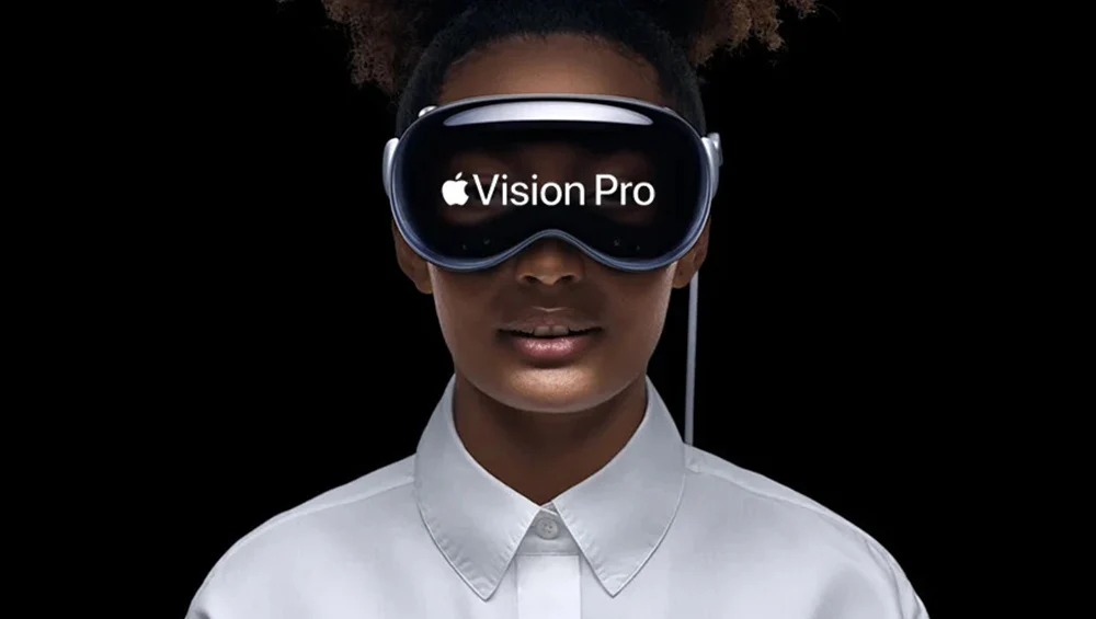 Apple Vision Pro headset showing the Vision Pro wordmark, worn against a black background