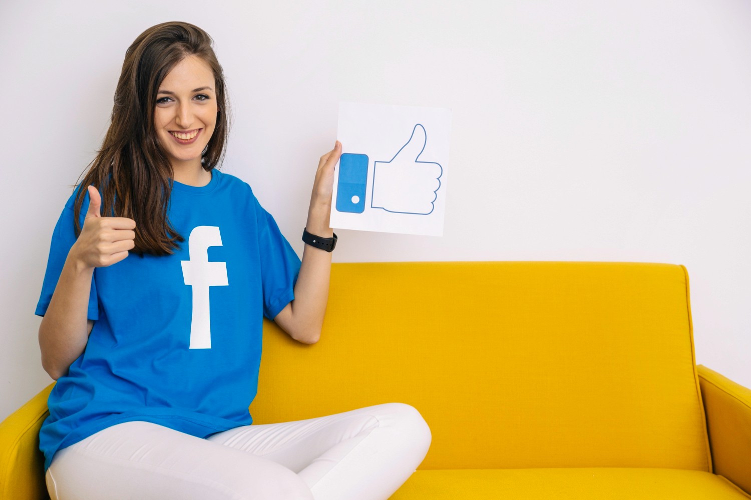  A woman smiling while holding a Facebook like sign, symbolizing social media engagement and positivity.