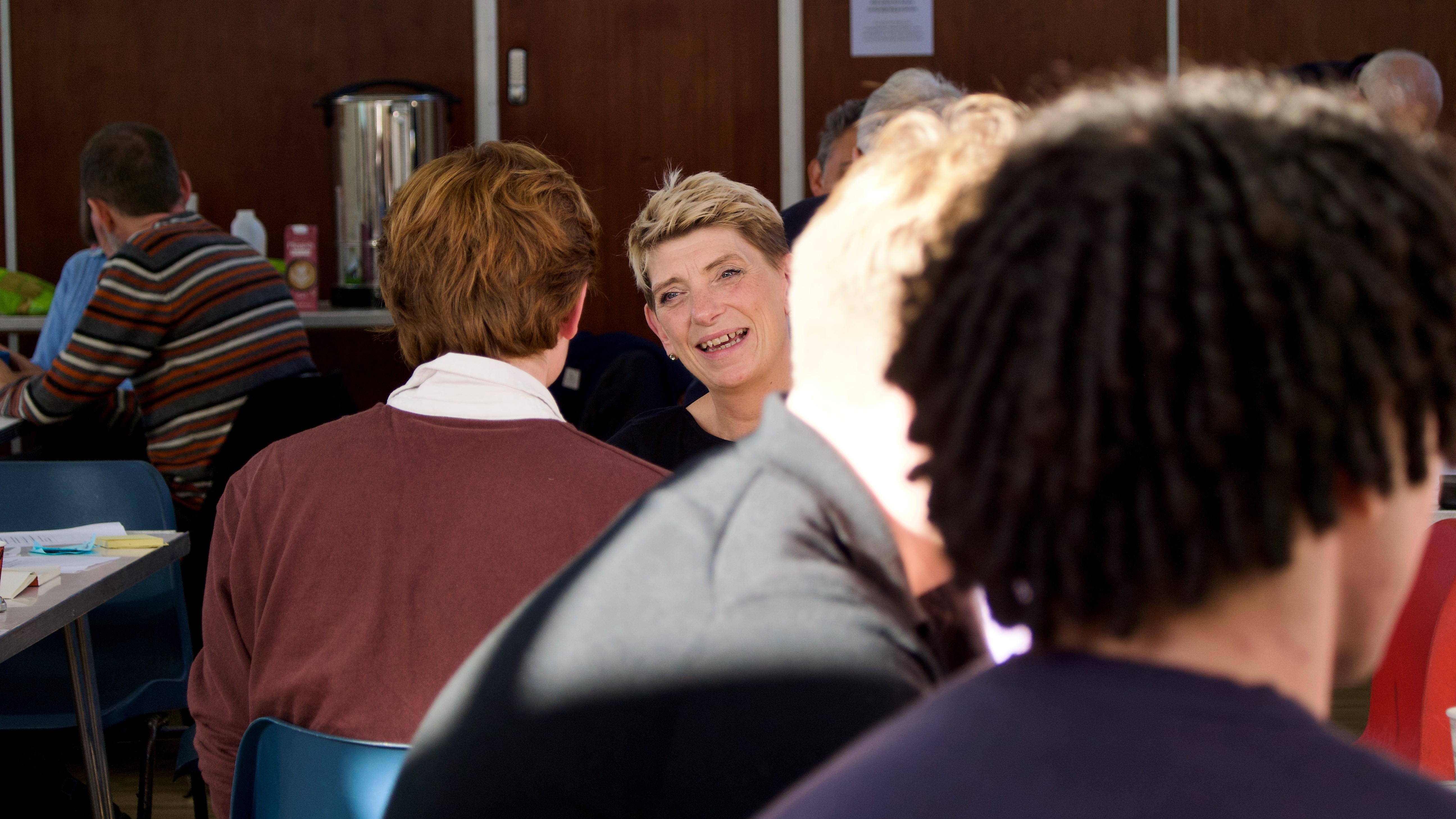 A woman talking with a young man at a table at community gathering.