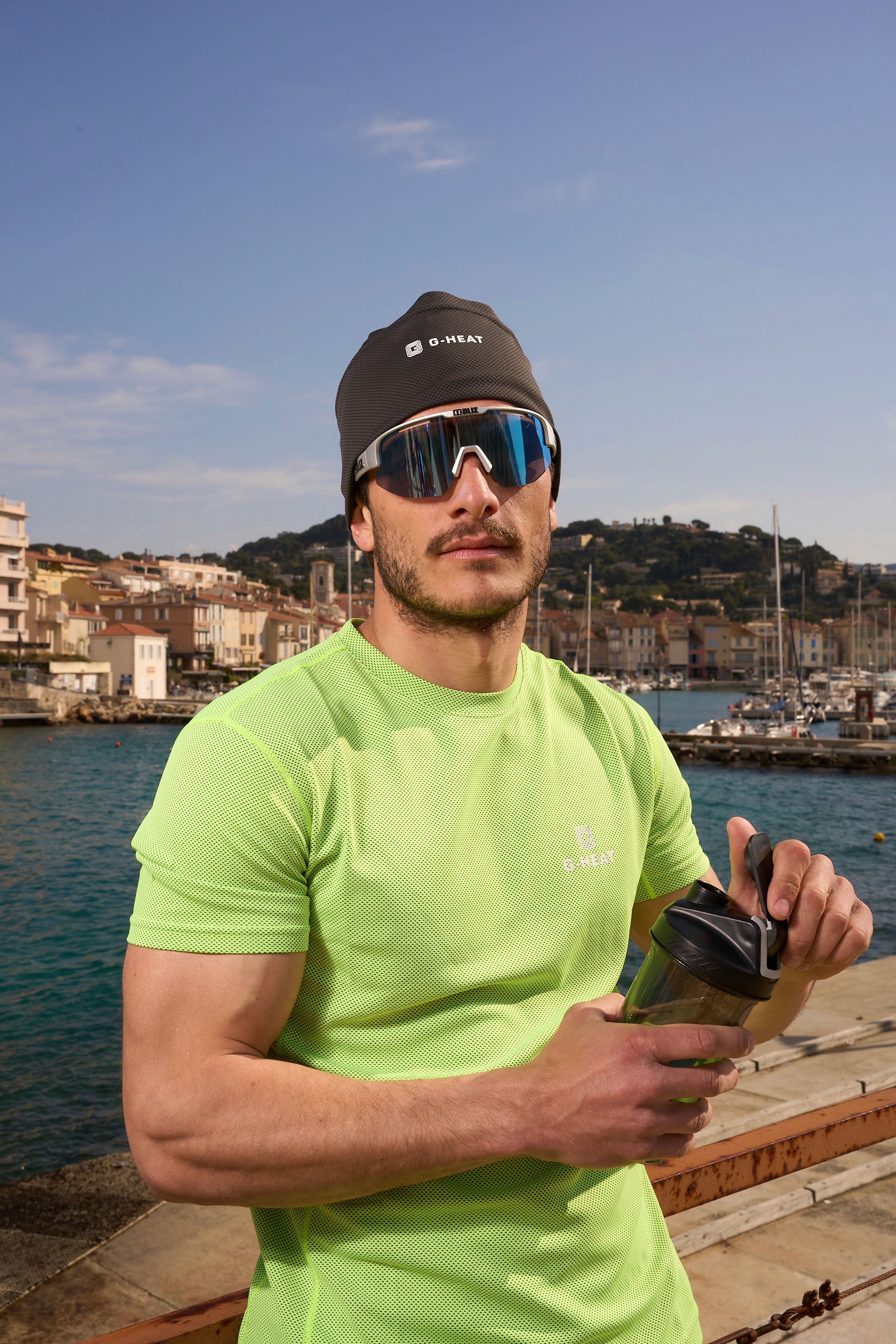 Man wearing a green G-Heat cooling t-shirt by the seaside in sunny weather