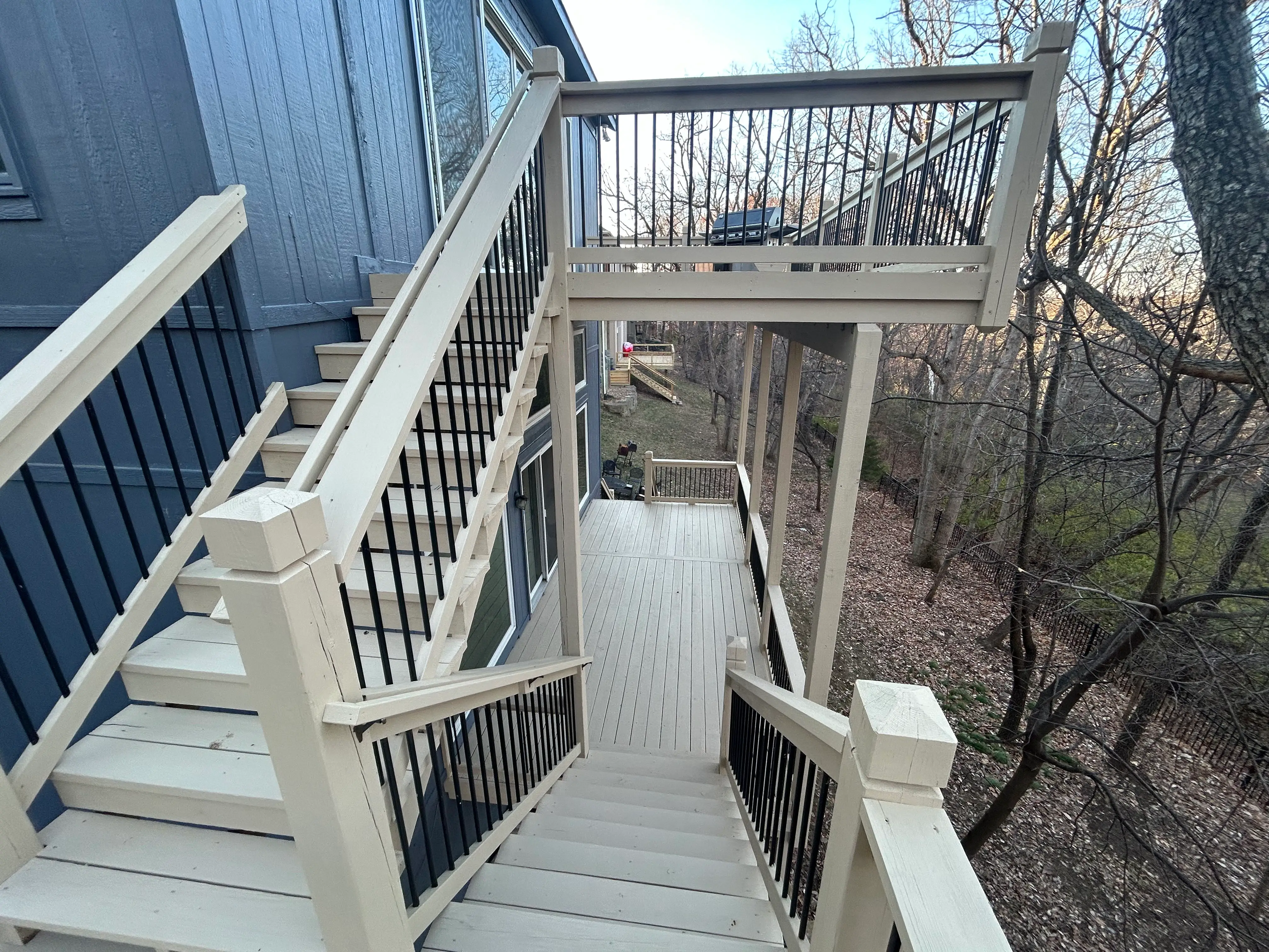 An image looking down to the second deck of a newly repaired white wood deck.