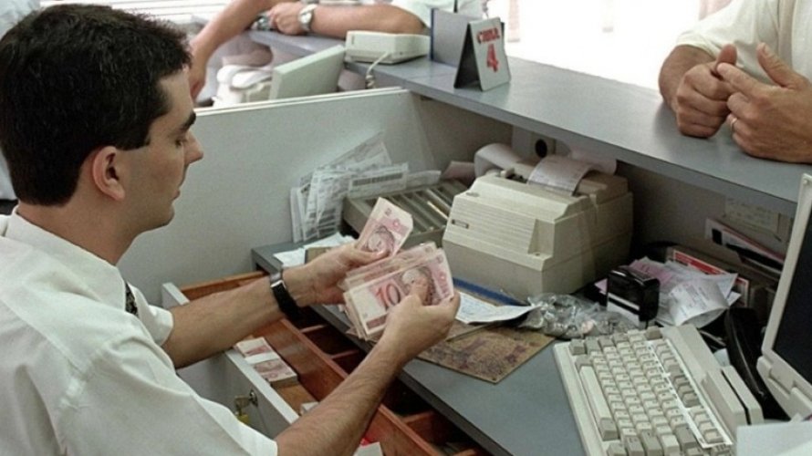 Cassiere conta banconote allo sportello: operazioni di cassa e gestione pagamenti