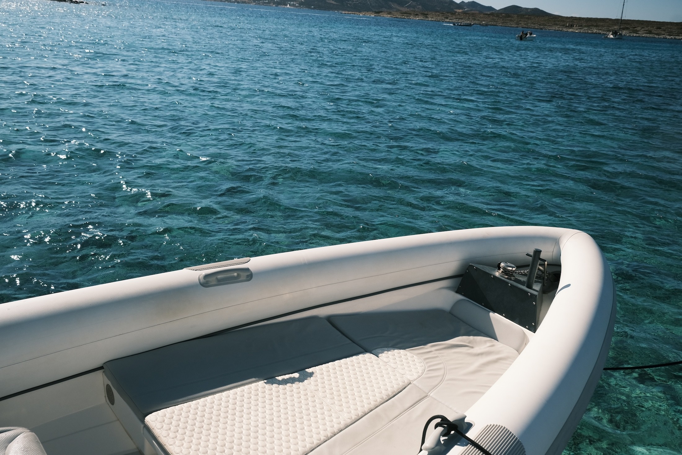 View from aboard the Airship 30 Aether yacht showing the bow deck and turquoise Aegean waters with Greek islands in the distance under clear blue skies.