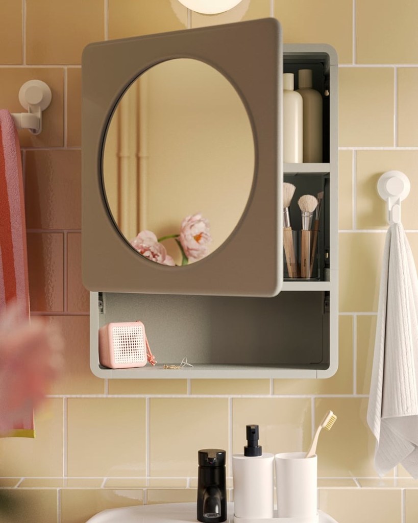 A bathroom scene featuring a wall-mounted cabinet with a round mirror, revealing organized toiletries and beauty products inside, against a backdrop of yellow tiled walls.