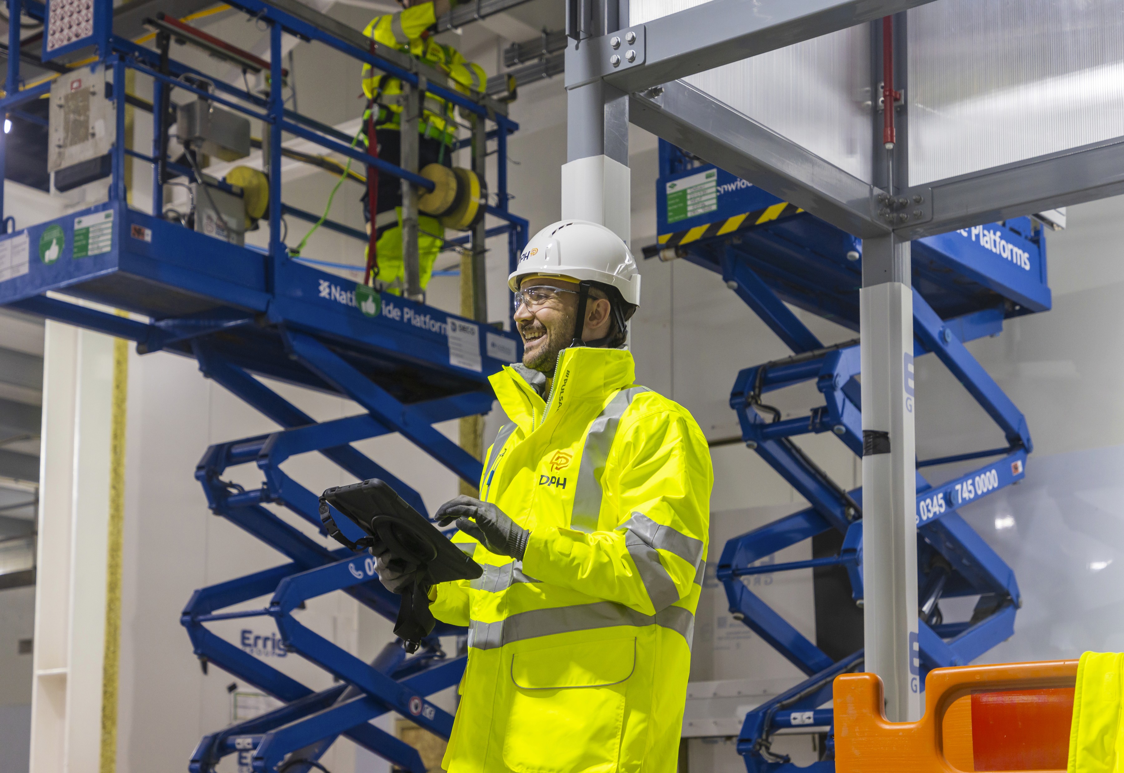Modern glass building with illuminated facade and trees at sunset