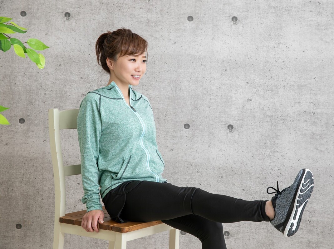 young woman doing a chair cardio workout for beginners at home