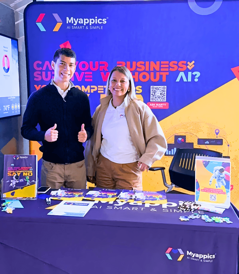 Black and white photo of two people looking at a computer screen with papers on wall