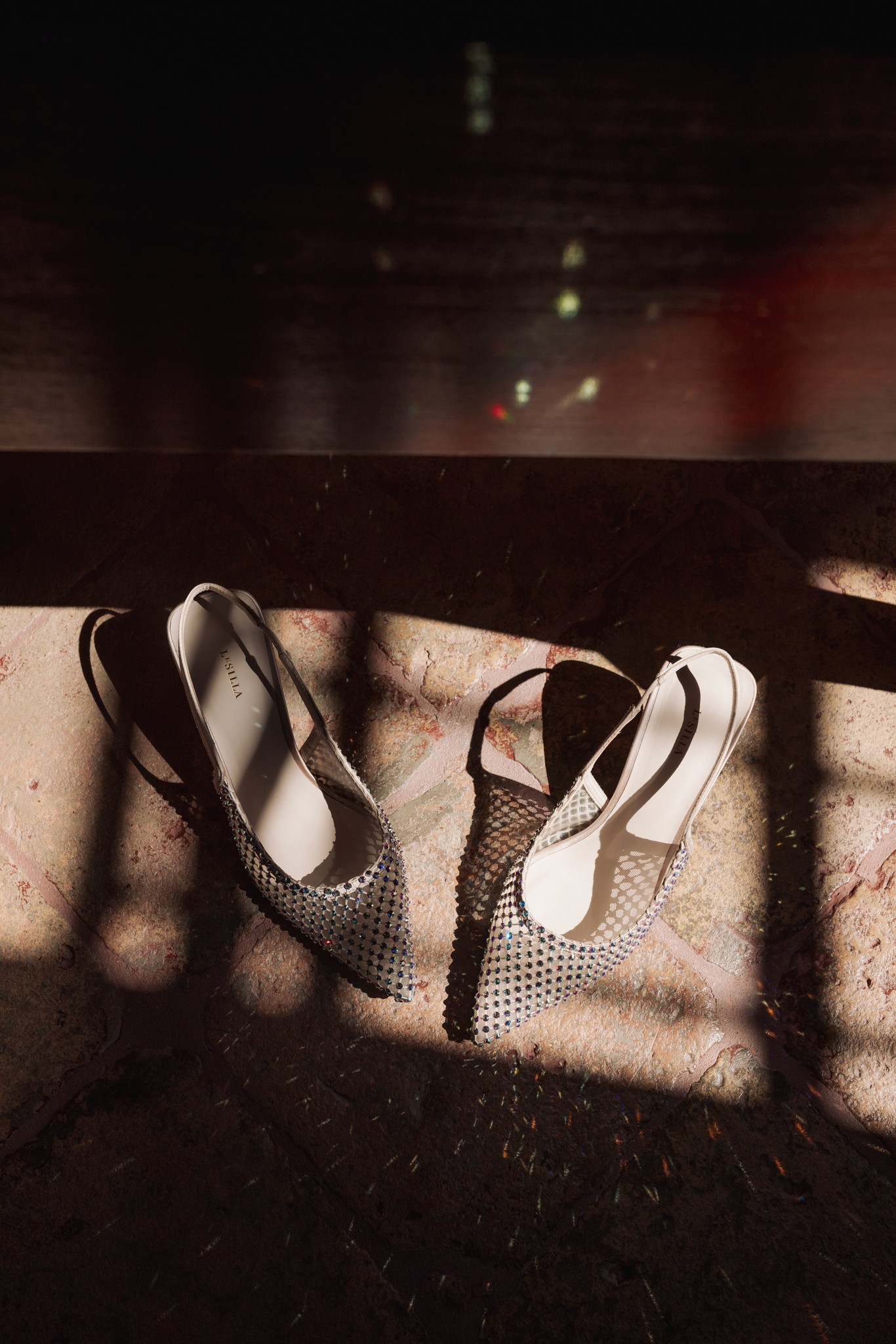Scarpe da sposa bianche e nere in luce naturale su tessuto grezzo, dettaglio dei preparativi al Castello di Scipione
