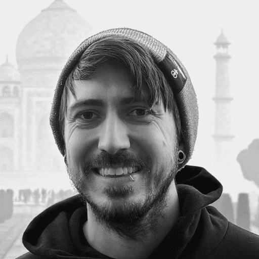 Photo of a smiling person in a hoodie in front of the Taj Mahal