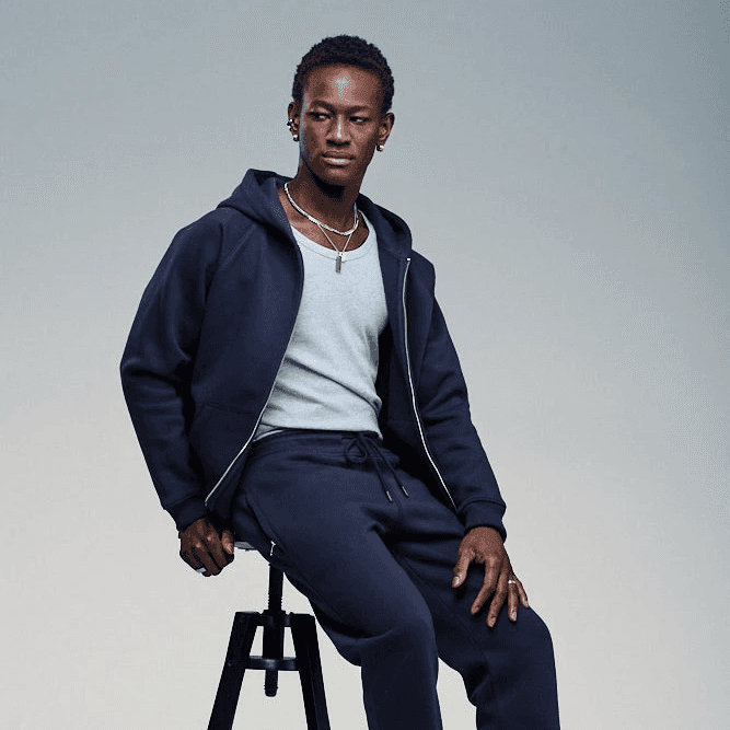 Man wearing matching navy sweatpants and zip hoodie in a studio setting