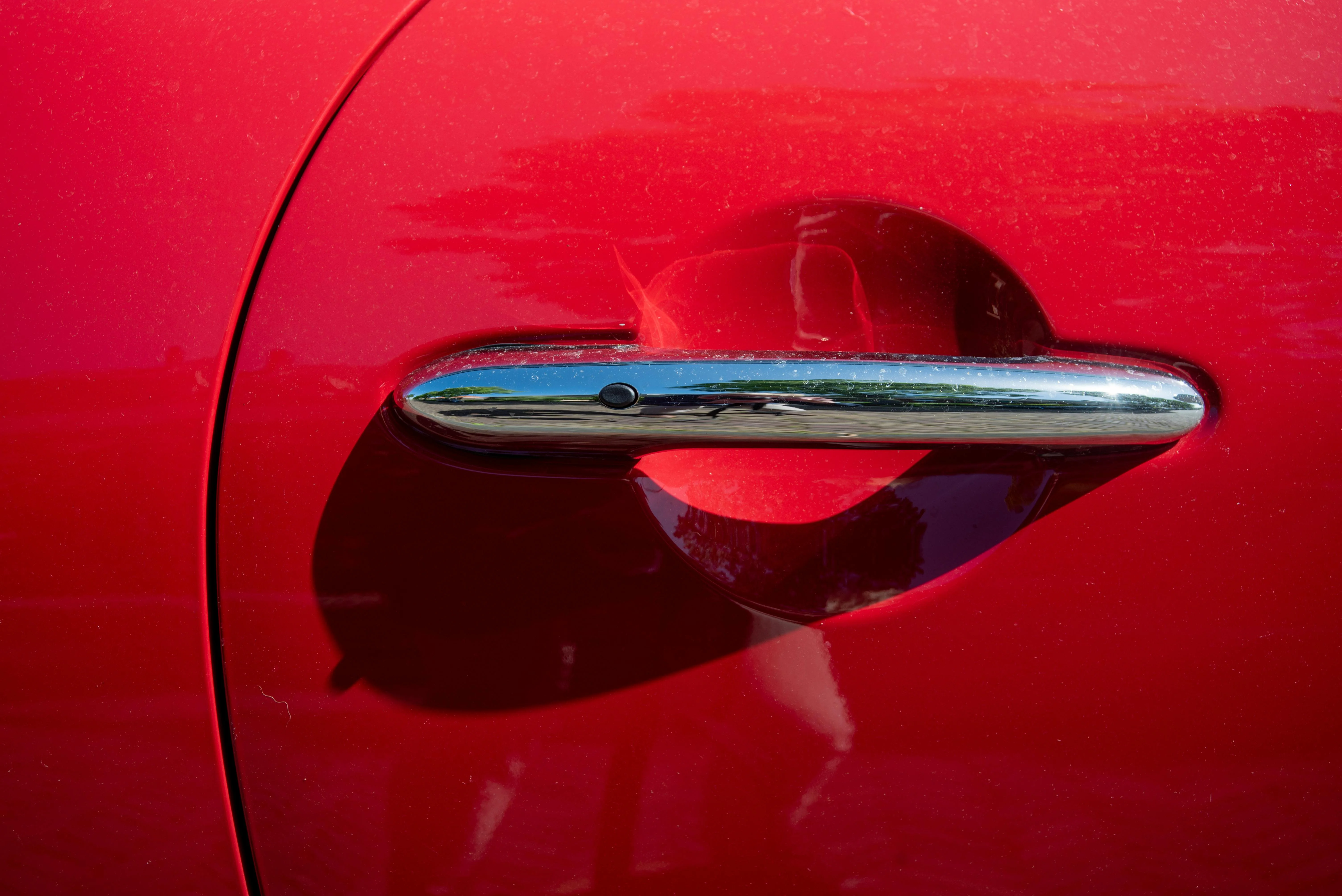 Poignée chromée sur une porte de voiture rouge.
