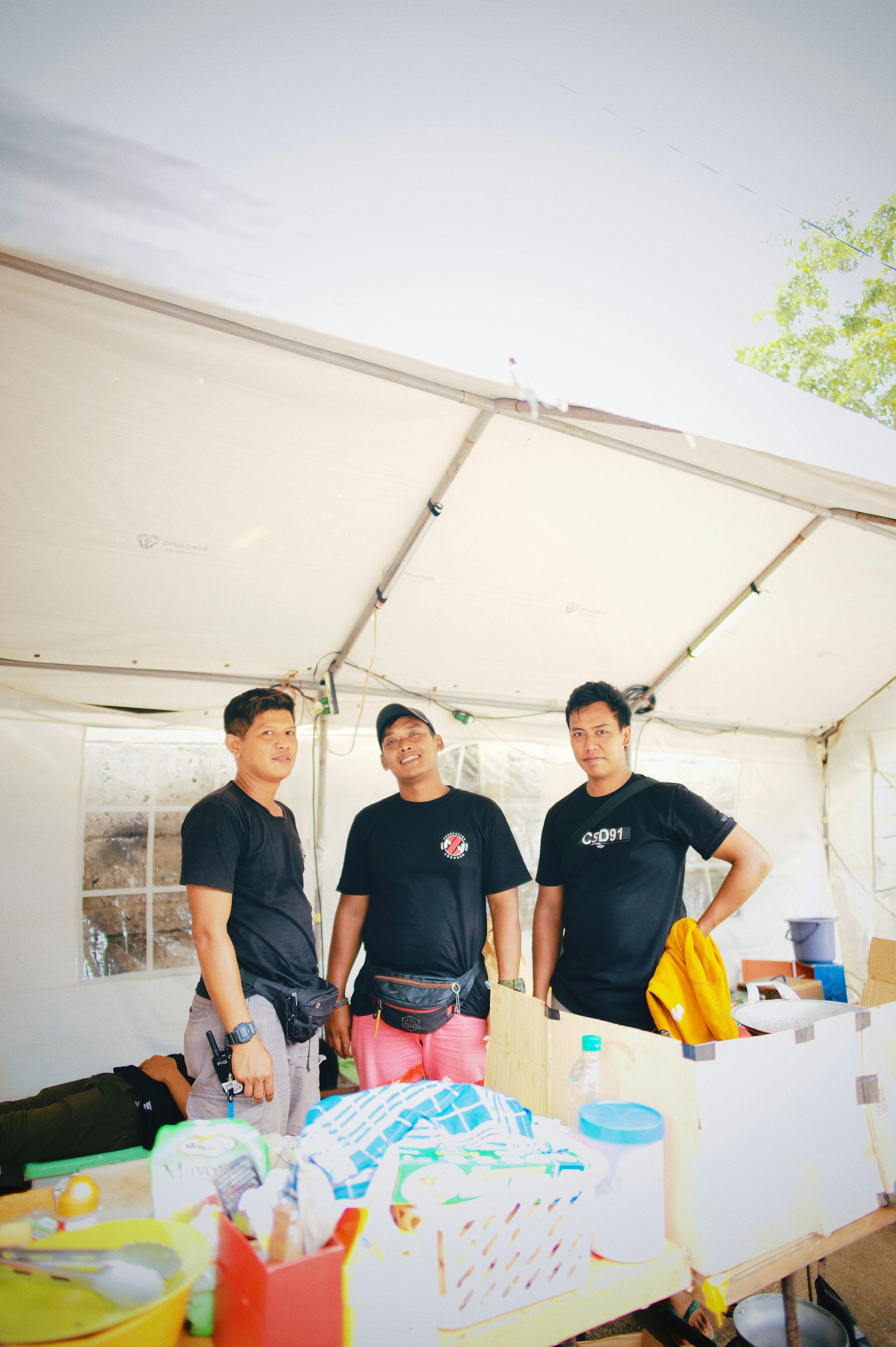 a group of men standing in a tent with a table and a white tent