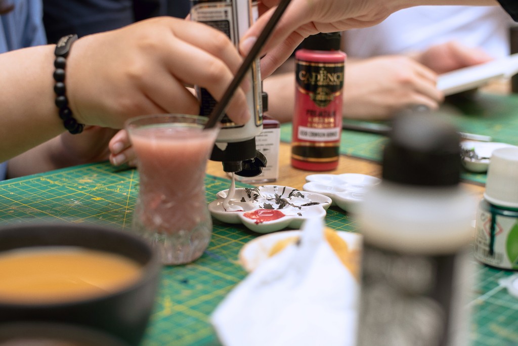 Close-up of a participant's hand painting intricate Turkish tile designs at a ceramic art workshop in Istanbul. Explore Turkish tile art and ceramic workshops as part of your Istanbul itinerary.