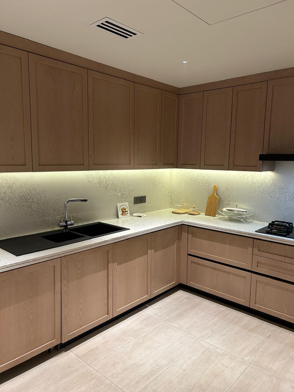 Minimalist kitchen with wood cabinetry, concealed handles, and ambient under-lighting.