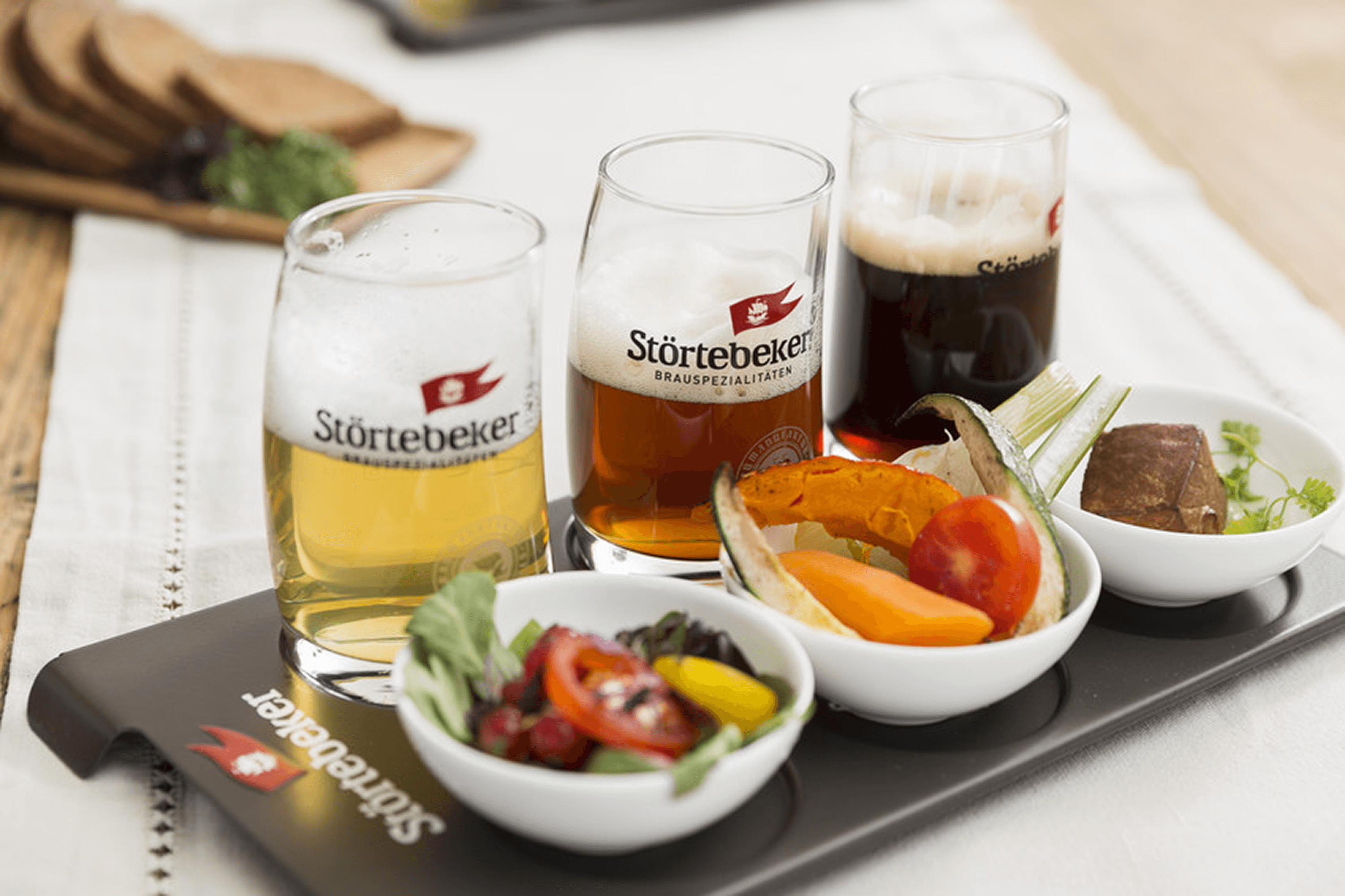 Three beers and small plates of food