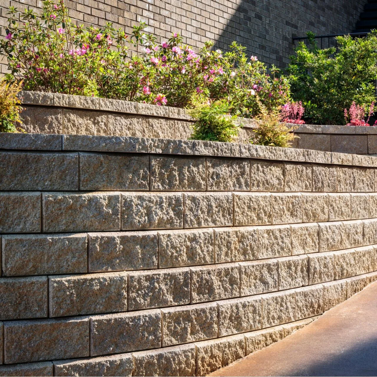 A planted retaining edge Tiered textured block retaining wall beneath a planted garden bed.
