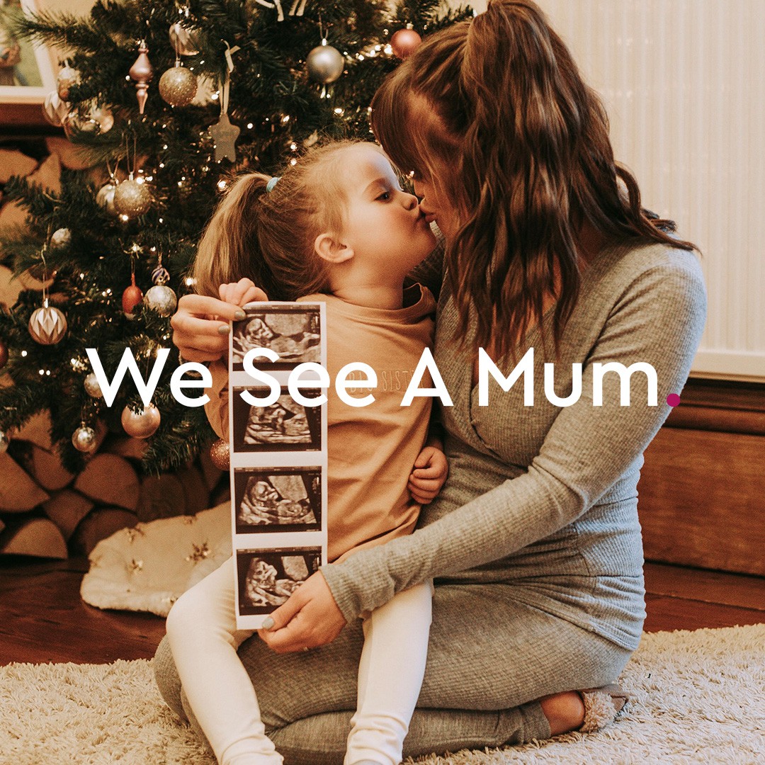 A woman kissing a child with some pregnancy scan photos