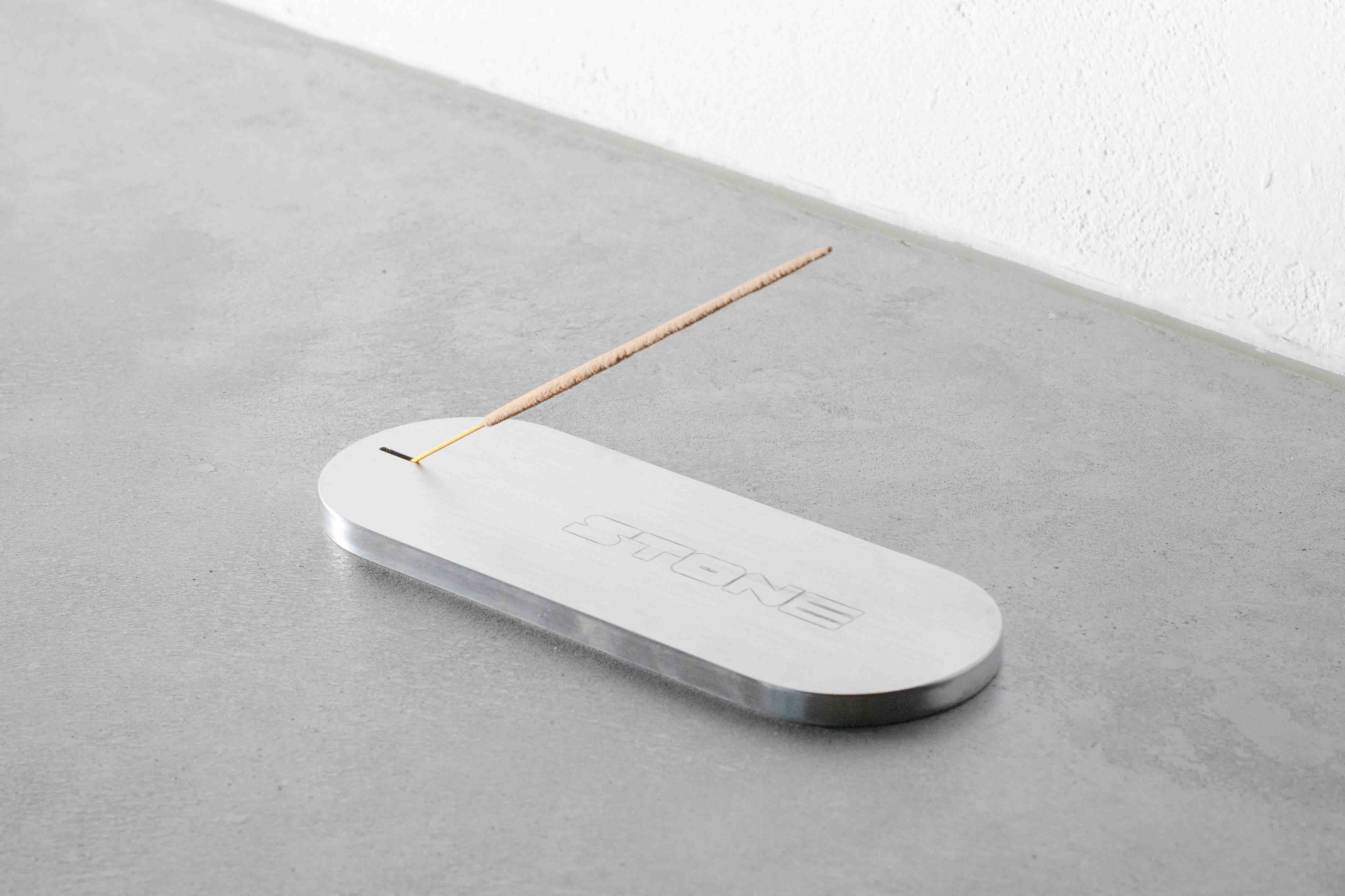 sideview of a metal incense holder on a concrete floor