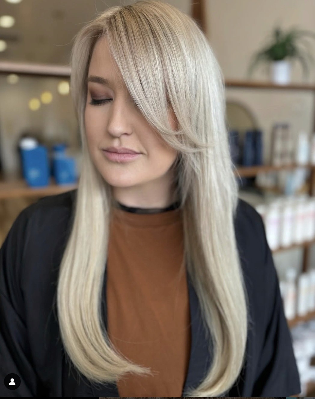 Woman with sleek, straight platinum blonde hair and soft side-swept layers, styled with a smooth, polished finish.