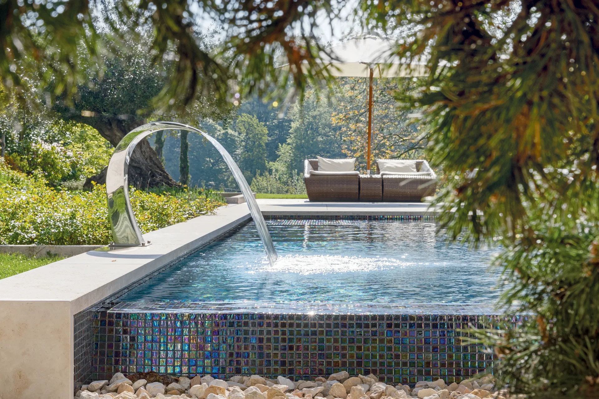 MLine pool with arched water jet and mosaic tiles in the garden