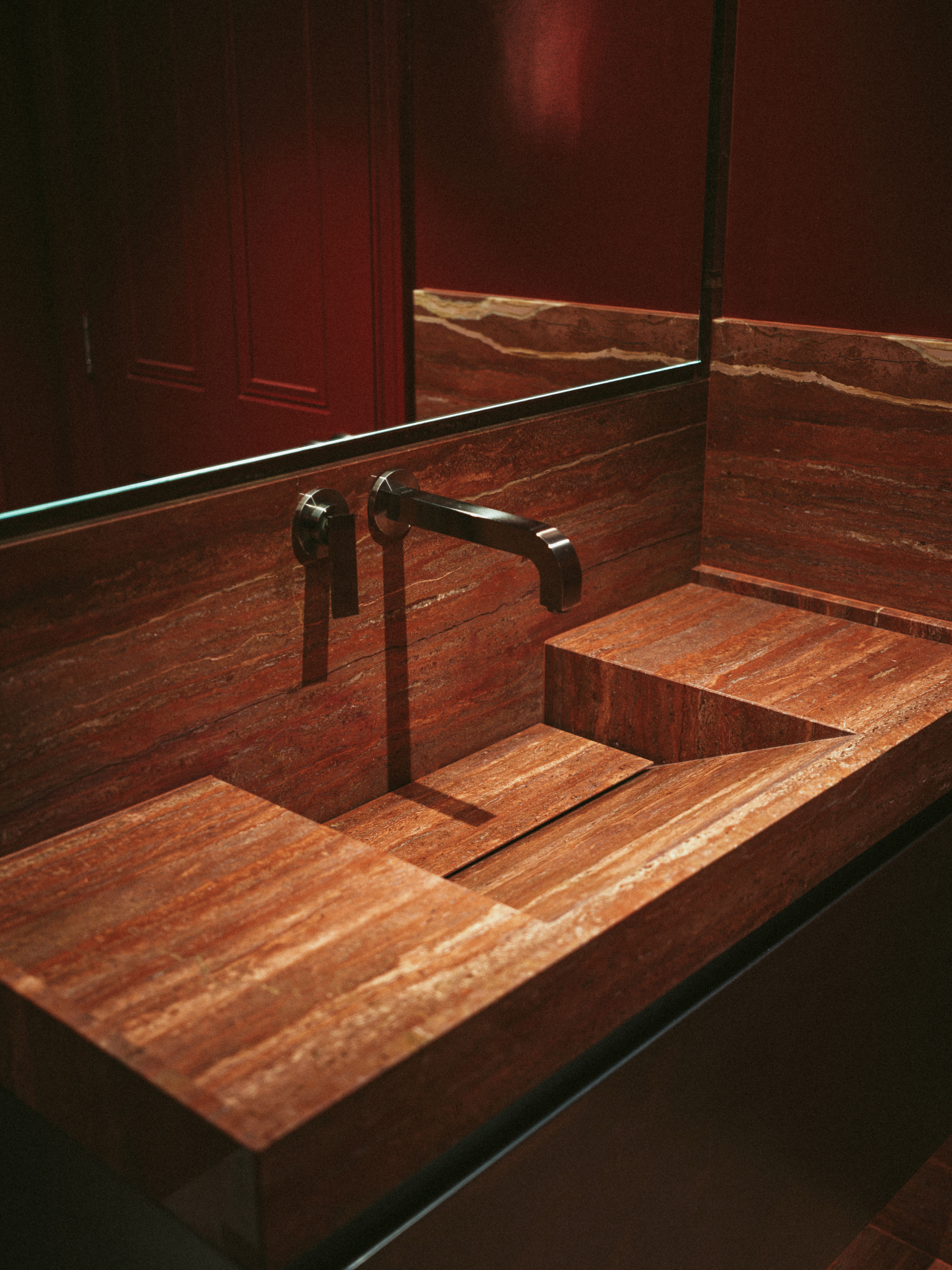 Red travertine stone sink and cladding with stainless steel cabinetry, stainless steel wall hung cabinetry