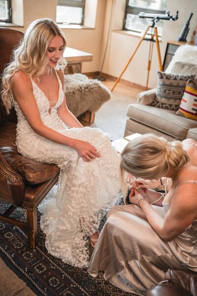 A bridesmaid helps with Clemmie's shoes while the bride sits in the cabin.