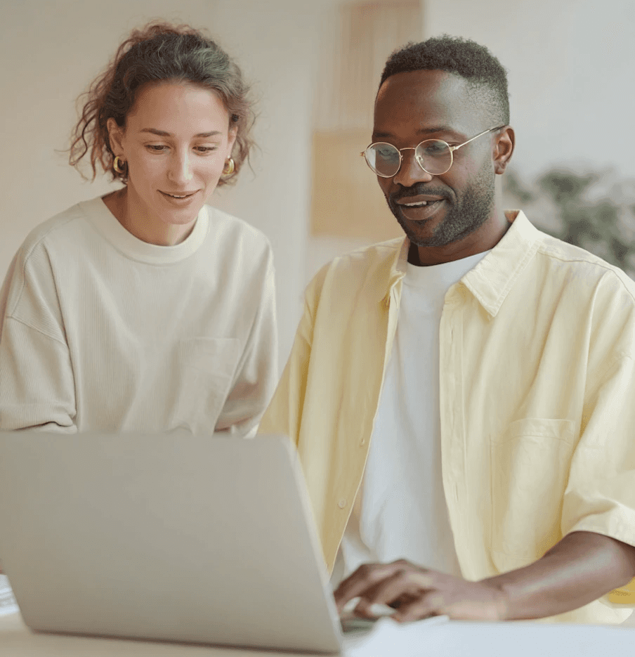 Woman with glasses and bearded man working on laptop together