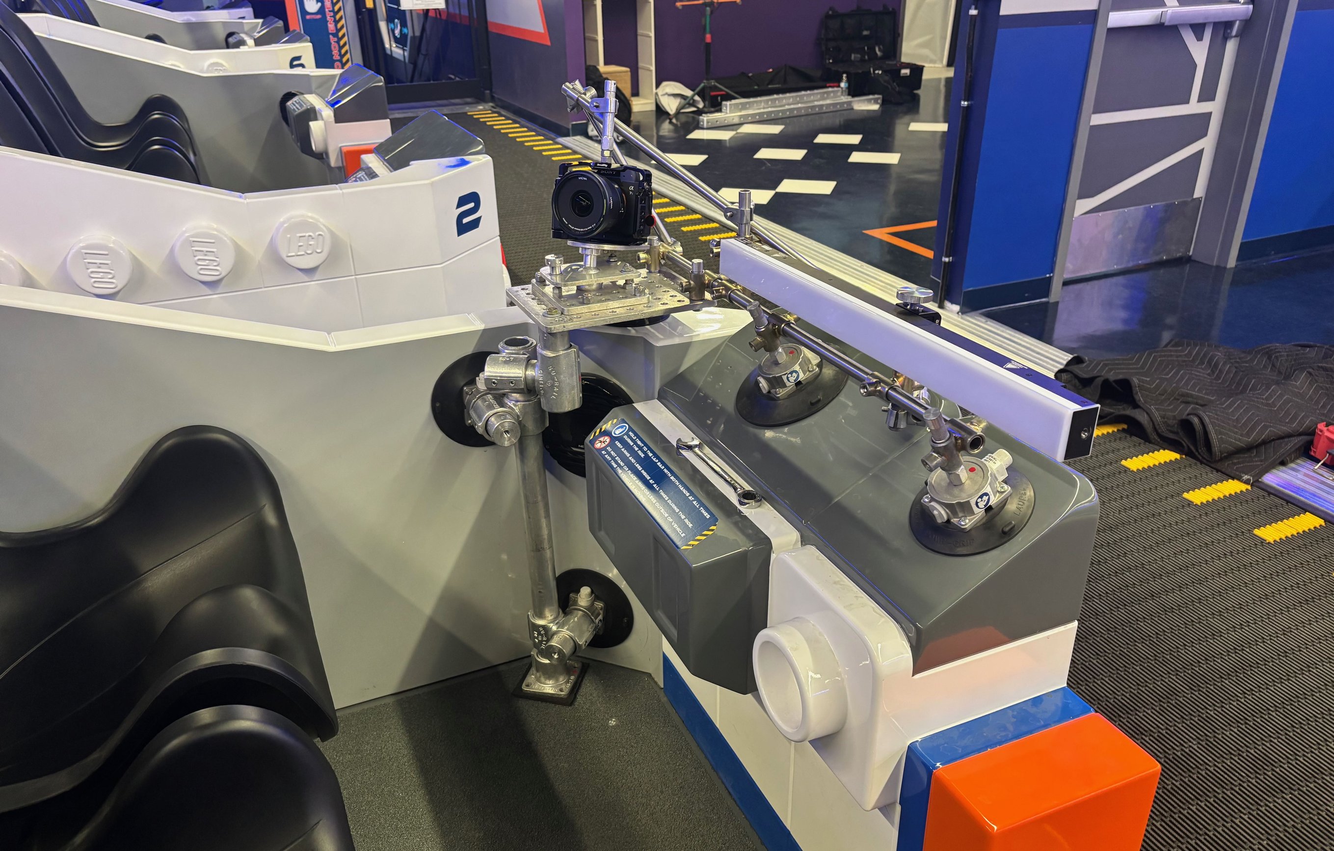 Detail of second camera rig on Legoland coaster showing suction cups on fiberglass panel with ratchet strap redundancy, speedrail assembly, and mounted camera