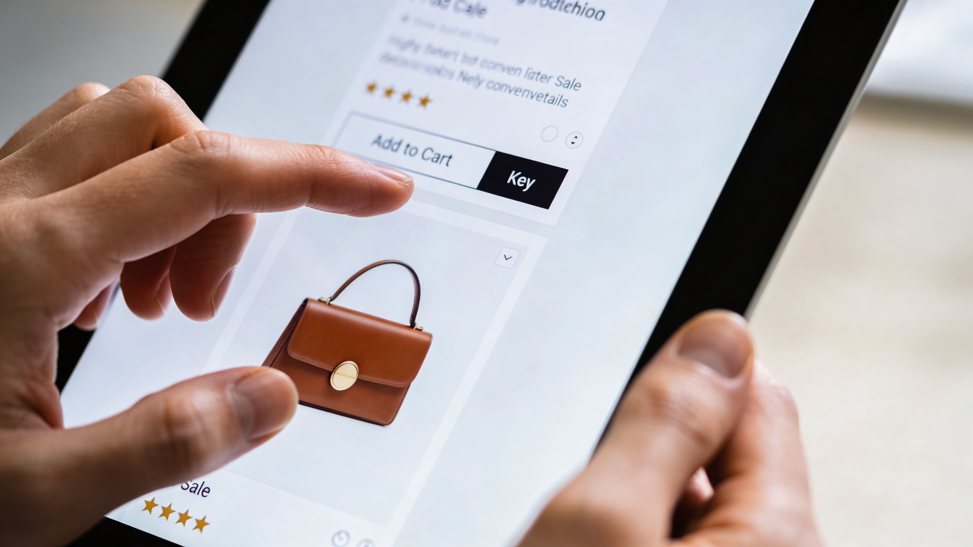 A close-up shot of a person using a tablet to browse an online store for leather bags.