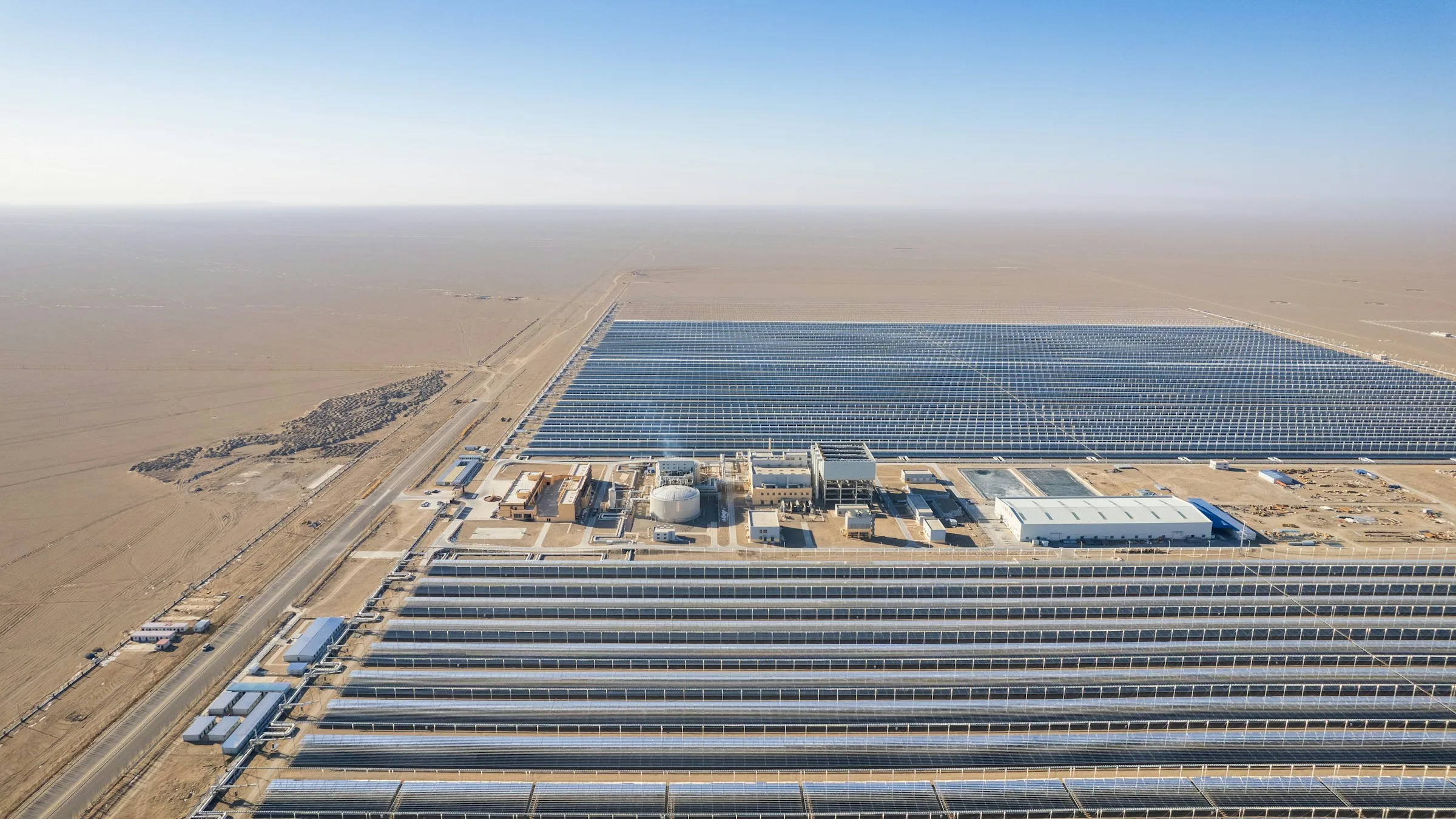Large utility-scale solar farm stretching across flat desert land with a substation in the distance